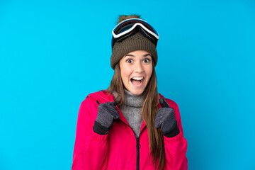 Teenager skier girl with snowboarding glasses over isolated blue background celebrating a victory