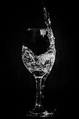 water falling into a wine glass on black background