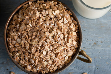 Healthy cereal flakes in a ceramic bowl. Rye flakes in a bowl on stone blue wooden background.