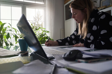 Woman Working at home in bathrobe. Social distancing and impact on jobs. Concerned woman...