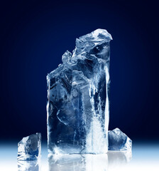 Vertical rectangular block of ice with a broken-off top isolated on a dark blue background with...