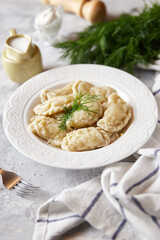 Christmas dumplings stuffed with mushrooms and cabbage on a white plate on a rustic wooden table. A traditional dish on Christmas Eve in Poland. Dumplings, dumplings, pies, pies - stuffed dumplings.