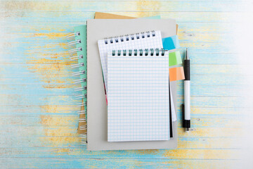 school spiral notepads with ballpoint pen on blue wooden background