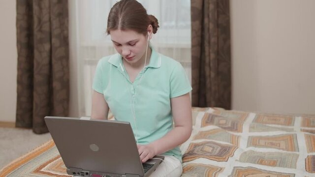 Studen girl with a serious look studying with distant teacher remote communication via laptop. Smart young woman learning new language talking with internet coach. Online education. Self-isolation.