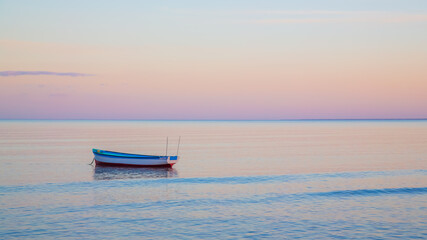 Fototapeta premium boat on calm ocean at sunset, background
