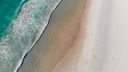 Einsamer Sandstrand aus der Vogelperspektive / Strand mit Meer und Brandung von oben
