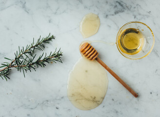 Honey on white marble top. Honey wood dipper is on drop of honey. Healthy sweet ingredient for natural cosmetics. Golden, yellow, raw honey. Top view