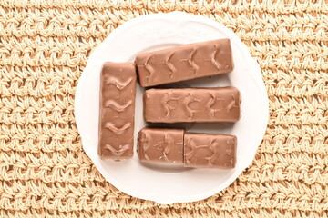 Close-up of four chocolate bars on a white plate on a straw mat.