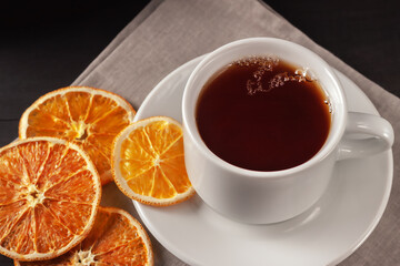 Cup of tea with dried orange slices on black wooden background