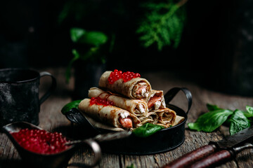 pancakes with red caviar fish and cream cheese on a wooden background