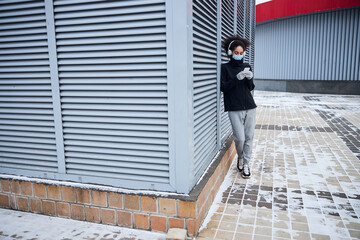 Athlete focused on her phone near a shutter wall