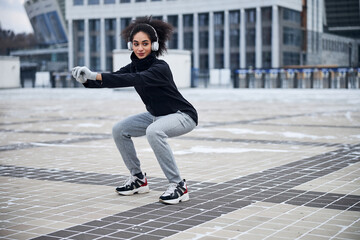 Content female performing squats during outdoor training