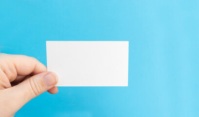 Hand holds a blank white business card on a blue background