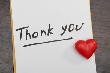 Schedule notepad on dark table with thank you inscription and red heart
