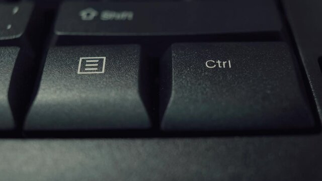 Person finger repeatedly pressing the ctrl key on a black office keyboard. Macro shot.