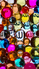 Fototapeta na wymiar A colorful glass ball bearing the name of Allah, perfect for smartphone or Islamic concept wallpapers. 