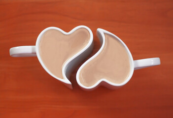 two heart shaped cups with hot drink on wooden table, top view