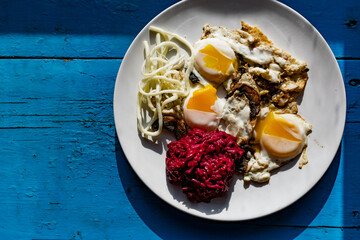 Fried eggs with mushrooms, long cheese noodles and beetroot caviar, a hearty fried dish for Breakfast with appetizers. The flowing liquid yellow egg yolk