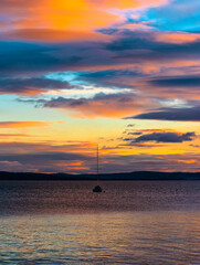 Sailboat in the colorful sunset, dusk with clouds at the lake Balaton.