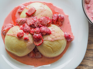 Polish traditional yeast dumplings steamed with strawberries and sugar in cream.
