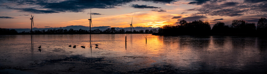 Beautiful sunset at Pen-y-fan pond with the pond completely frozen over with turbines in background, located in Blackwood,Wales UK