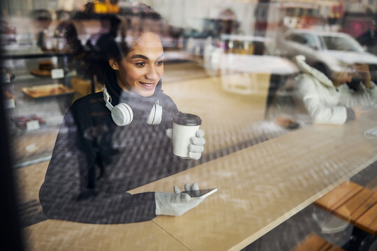 Woman dialing a number on a phone while sipping coffee