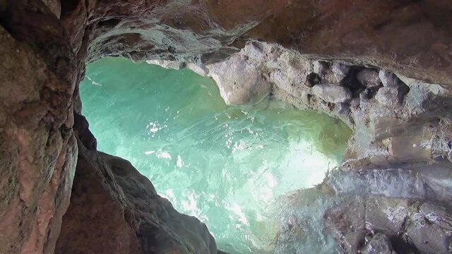 A large hole dug by water over the centuries in the rock of a mountain along the coast.