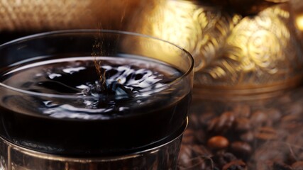 Drop of Turkish coffee falling in glass cup.