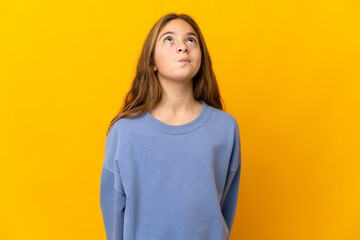 Child over isolated yellow background and looking up