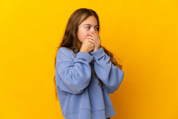 Child over isolated yellow background covering mouth and looking to the side