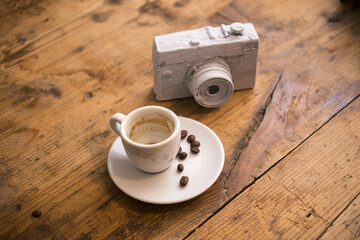 empty cup of coffee ,roasted coffee beans and painted vintage camera on old wood background