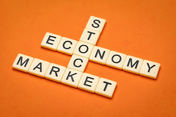 stock market and economy crossword in ivory letter tiles against textured handmade paper, business and finance concept