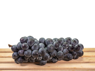 The close up of ripe organic black seedless grape bunch, healthy juicy berry fruits on wooden plank on white background.