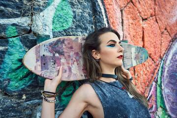 Young woman with urban style, she poses with a long board.