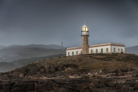 Punta Insua or Lari&radic;&plusmn;o lighthouse on a foggy sunset. Galicia, Spain.
