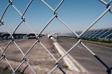 close up of chain link fence with wire in front of solar energy
