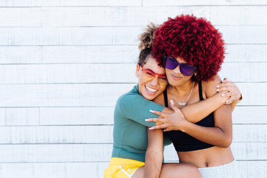 Two attractive latin girls with afro hair hugging each other amicably.