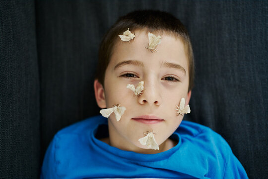 Boy with serious look posing with silkworm butterflies on his fa