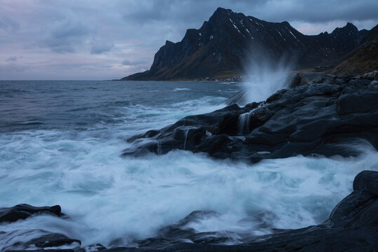 Bj&radic;&prod;rntind mountain peak rises over rocky coastline near village of Vikten, Flakstad&radic;&prod;y, Lofoten Islands, Norway