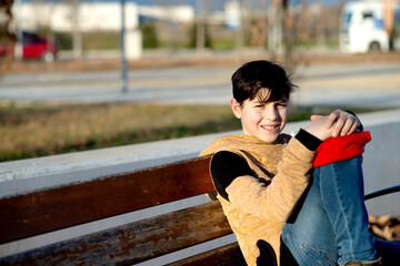 Young boy sitting on a bench while looking at the camera