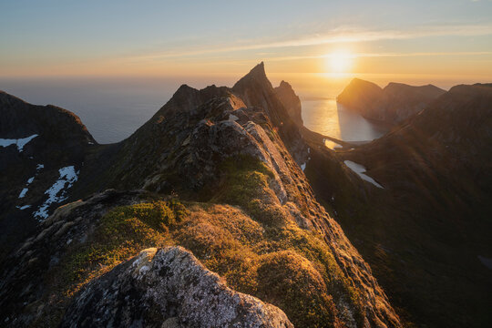 June midnight sun hangs low over sea above Kvalvika beach, Lofotodden national park, Moskenes√∏y, Lofoten Islands, Norway