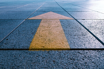 Close up of yellow arrow on street