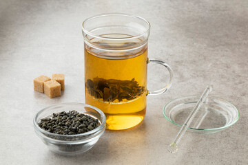 Tea glass with green gunpowder tea and a bowl with dried tea leaves