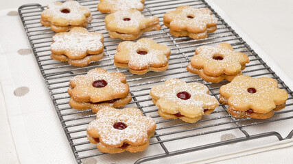 Flower shaped shortbread cookies filled with raspberry jam. Fresh baked cookies close up on cooling rack