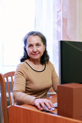 Smiling mature middle aged business woman  working on computer sitting at desk