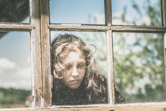 Sad Face Of Blond Girl Behind The Window