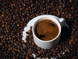 Close-up of a white espresso cup on a table with lots of coffee beans
