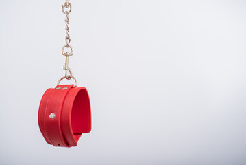 Red leather handcuffs on a white background. BDSM accessory for women