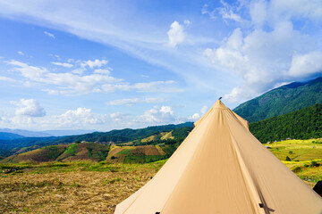 Tourist tent camping on the hill beneath the mountains under dramatic sky and golden terrace fields view in Chiangmai , northern of Thailand.