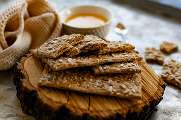 Healthy and nutritious diet bread with sesame and sunflower seeds on a thin crunchy malt base. Near natural bee honey and a wooden stand sawn